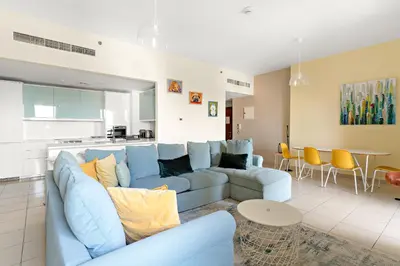 a living room with a blue couch and a table at VayK - Light-Filled and Spacious 1BR in JBR in Dubai