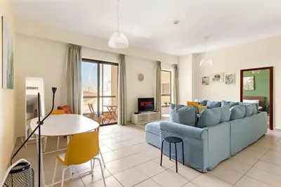 a living room with a blue couch and a table at VayK - Light-Filled and Spacious 1BR in JBR in Dubai