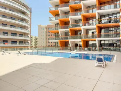a swimming pool in front of a building at VayK - Chic Studio in Silicon Oasis with Pool View in Dubai