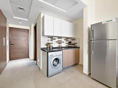 a kitchen with a washing machine and a refrigerator at Trendy Luxe Studio In Al Furjan close to Metro-17 in Dubai