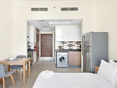 a kitchen and living room with a refrigerator and a table at Trendy Luxe Studio In Al Furjan close to Metro-17 in Dubai