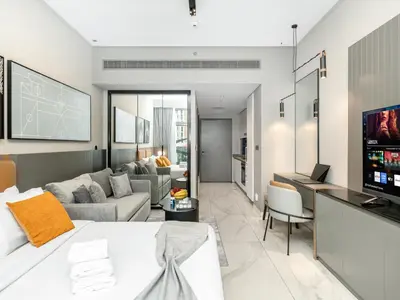 a living room with a couch and a table with a television at Cozy Studio with Balcony I Near Dubai Mall & Downtown in Dubai