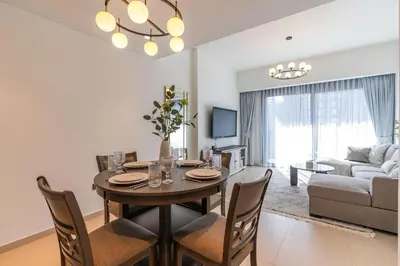 a dining room and living room with a table and chairs at Chic Downtown Act Tower Walk to Burj Khalifa&Mall in Dubai