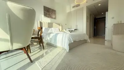 a bedroom with a bed and a chair and a table at Modern Luxury Studio Damac Hills With Golf View in Dubai