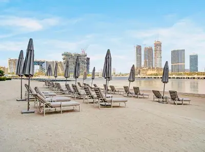 a group of chairs and umbrellas on a beach at Exquisite Beachfront 1BR l Palace Beach Residence in Dubai
