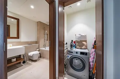 a bathroom with a washing machine and a sink at Exquisite Beachfront 1BR l Palace Beach Residence in Dubai