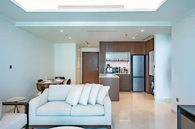 a living room with a white couch and a kitchen at Exquisite Beachfront 1BR l Palace Beach Residence in Dubai
