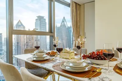a dining room with a table with food and wine glasses at Iconic Burj Khalifa View 2BR Luxury apmt at Paramount Midtown in Dubai