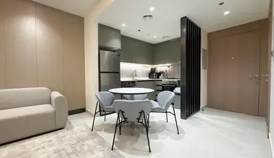 a living room with a table and chairs and a kitchen at Werova - Modern 1BR Apartment Prime JVT Location in Dubai