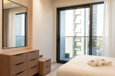 a bedroom with a bed and a large window at Werova - Modern 1BR Apartment Prime JVT Location in Dubai