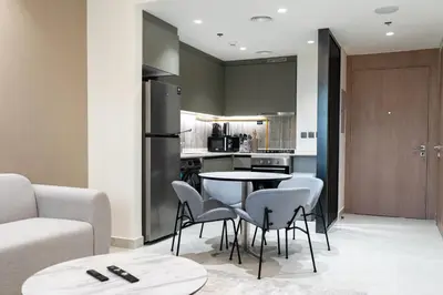a kitchen and living room with a table and chairs at Werova - Modern 1BR Apartment Prime JVT Location in Dubai