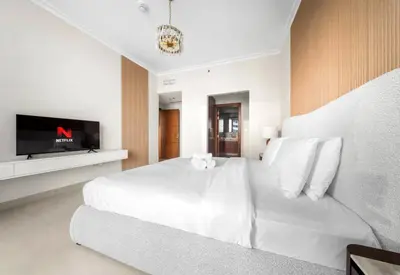 a white bedroom with a large bed and a tv at Exclusive Apartments in Burj Vista Downtown Dubai Near Burj Khalifa in Dubai