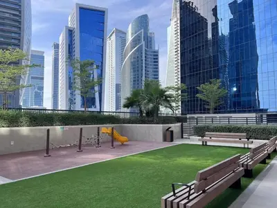 a park with benches and a playground with tall buildings at Luxurious 1 BDR Zada Tower Business Bay 12 in Dubai