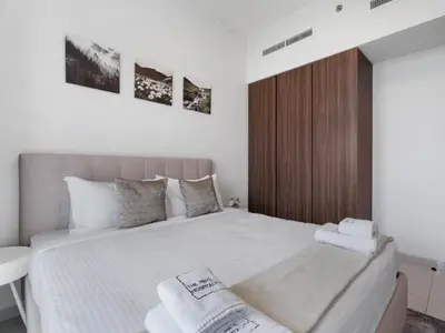 a bedroom with a large bed with two towels on it at Reva Residence Comfort Suite 1BDR Plus Sofa Bed in Dubai
