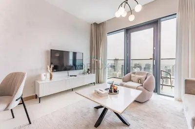 a living room with a tv and two chairs and a table at Prime Location with Direct Mall and Marina Walk Access, Just Outside DMCC Metro Station - VIDA Residences, Dubai Marina by Deluxe Holiday Homes in Dubai