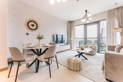 a living room with a table and chairs and a couch at Prime Location with Direct Mall and Marina Walk Access, Just Outside DMCC Metro Station - VIDA Residences, Dubai Marina by Deluxe Holiday Homes in Dubai