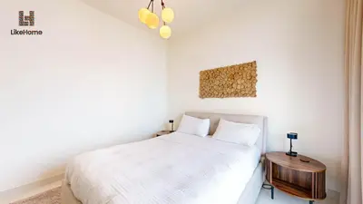 a bedroom with a white bed and a wooden table at Stunning 2BR Beachfront Living Marina Vista Tower 2 in Dubai
