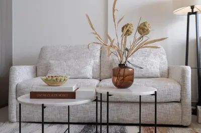 a living room with a couch and a vase on two tables at Chic Pool-View Studio Oxford Gardens by Czechin in Dubai