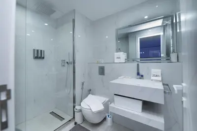 a bathroom with a shower and a toilet and a sink at Escape 24 Spacious 1BR Lake View, Global Lake View, JLT in Dubai