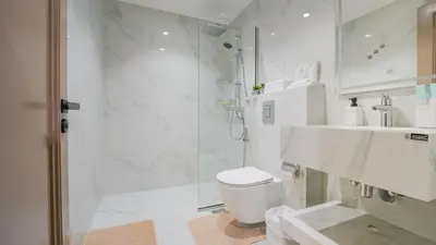 a white bathroom with a shower and a toilet at Contemporary one-bedroom apartment in Burj Khalifa area by Norbu Holiday Homes in Dubai