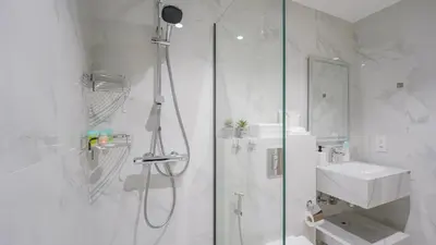 a white bathroom with a shower and a sink at Contemporary one-bedroom apartment in Burj Khalifa area by Norbu Holiday Homes in Dubai