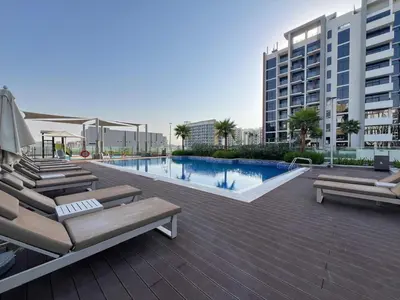a swimming pool with lounge chairs and a building at The Comfort Cove Studio in Azizi Riviera 32 in Dubai