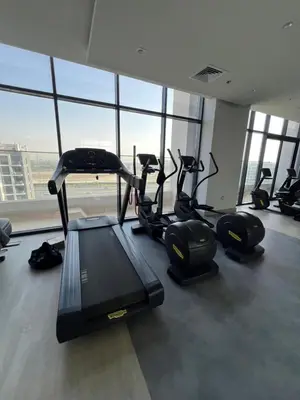 a gym with cardio equipment in a building with windows at The Comfort Cove Studio in Azizi Riviera 32 in Dubai