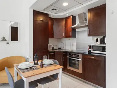 a kitchen with wooden cabinets and a table with chairs at The Havenette comfy Studio in 29 BLVD Walk in Dubai