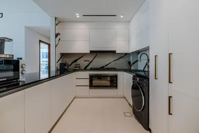 a kitchen with white cabinets and a washer and dryer at TRPS - Trillionaire Residences, Business Bay - Private Jacuzzi, Modern 2BR Furnished, Canal View in Dubai