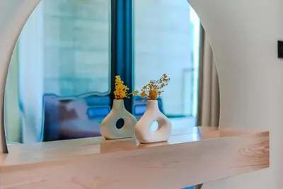 two white vases with flowers sitting on a table at TRPS - Trillionaire Residences, Business Bay - Private Jacuzzi, Modern 2BR Furnished, Canal View in Dubai