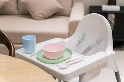 a white high chair with a plate and cups on it at SettlerHomes - Chic Cloud B - Pool, Gym & Court in Dubai