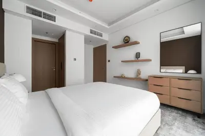 a white bedroom with a white bed and a television at SettlerHomes - Chic Cloud B - Pool, Gym & Court in Dubai