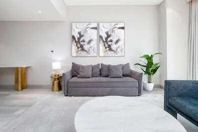 a living room with a couch and two paintings on the wall at Bright & Modern 1BR in Dubai Marina in Dubai