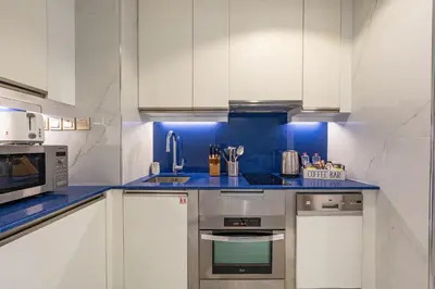 a kitchen with white cabinets and blue counter tops at Marina View Studio with Balcony in Dubai