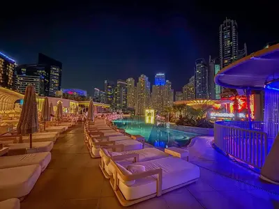 a rooftop bar with a pool and a city at night at Marina View Studio with Balcony in Dubai