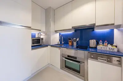 a kitchen with white cabinets and a blue wall at Marina View Studio with Balcony in Dubai