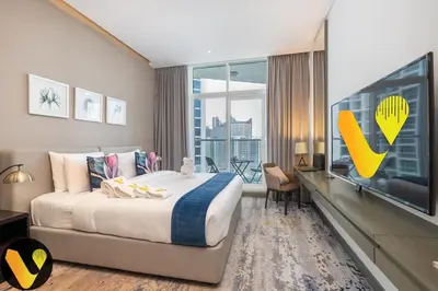 a hotel room with a large bed and a large tv at Vogue Business Bay Damac Maison Prive near Burj Khalifa and Dubai Mall, Studio Apartment with Balcony, City and Canal View, Access to all Amenities in Dubai
