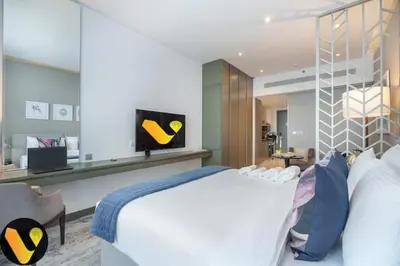a bedroom with a large white bed and a flat screen tv at Vogue Business Bay Damac Maison Prive near Burj Khalifa and Dubai Mall, Studio Apartment with Balcony, City and Canal View, Access to all Amenities in Dubai