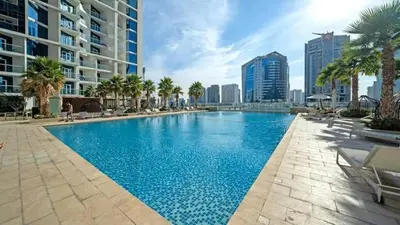 a large swimming pool with palm trees and buildings at Vogue Business Bay Damac Maison Prive near Burj Khalifa and Dubai Mall, Studio Apartment with Balcony, City and Canal View, Access to all Amenities in Dubai