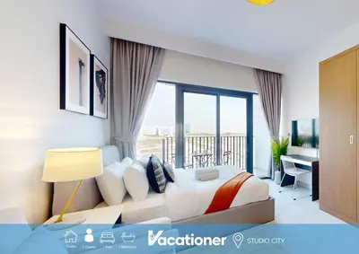 a bedroom with a bed and a desk with a window at Vacationer l Modern Studio l Community Views l Free Gym, Pool in Dubai