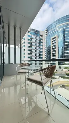 two chairs and a table on a balcony with buildings at Studio in central location with Balcony nearby Metro in Dubai