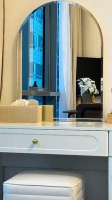 a dressing table with a mirror and a vase of flowers at Studio centrally located with a huge private balcony in Dubai