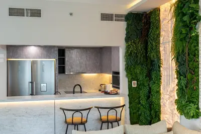 a kitchen with three chairs and a counter with a green wall at Werova - Luxury 2BR Apartment w Breathtaking View in Dubai