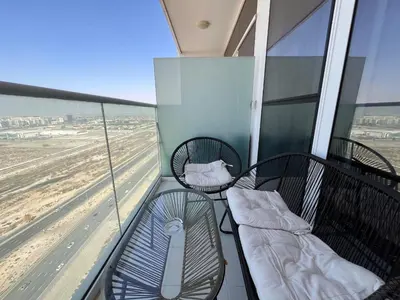 a balcony with two chairs and a bed on it at Modern 1BR Apartment Golf View Gym Pool in Dubai