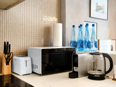 a kitchen counter with a microwave and blue bottles at Sky-high 1Br Apartment Sleeps 4 in Damac Paramount in Dubai