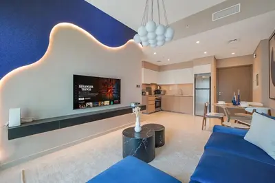 a living room with a blue couch and a tv at Downtown Suite Trendy 1BR -Dubai Mall Access in Dubai