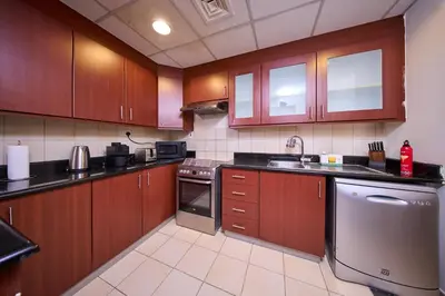 a kitchen with wooden cabinets and a stainless steel dishwasher at JBR 2BR with Iconic Palm Views Sadaf 6 Luxury in Dubai