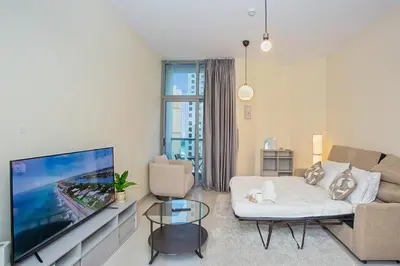 a living room with a couch and a large tv at Cozy 2 Bedroom Apartment with Balcony Near JBR Beach in Dubai