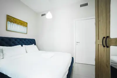 a bedroom with a white bed and a door at Cozy 2 Bedroom Apartment with Balcony Near JBR Beach in Dubai