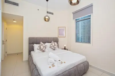 a bedroom with a large bed with white sheets and pillows at Cozy 2 Bedroom Apartment with Balcony Near JBR Beach in Dubai